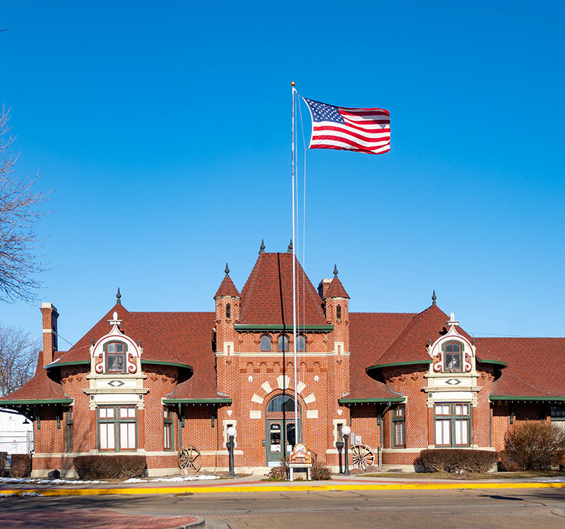 Nampa Train Depot Museum with an American flag in front with a bright blue sky.