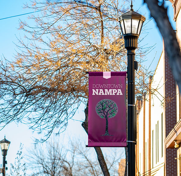 Downtown Nampa sign with Downtown Nampa and a tree on the banner. The banner is hung on a light post.