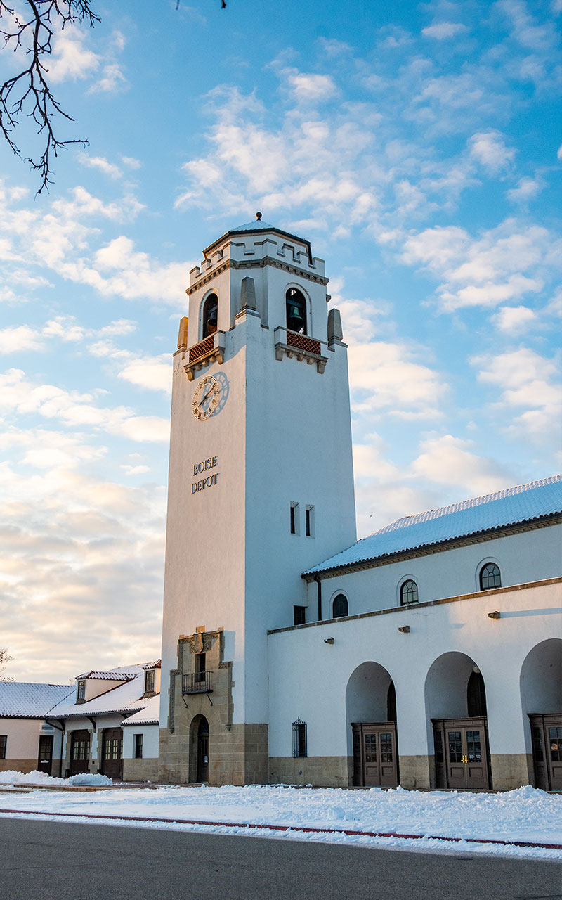 The old Boise train depot with snow on the ground an cloudy blue skies.