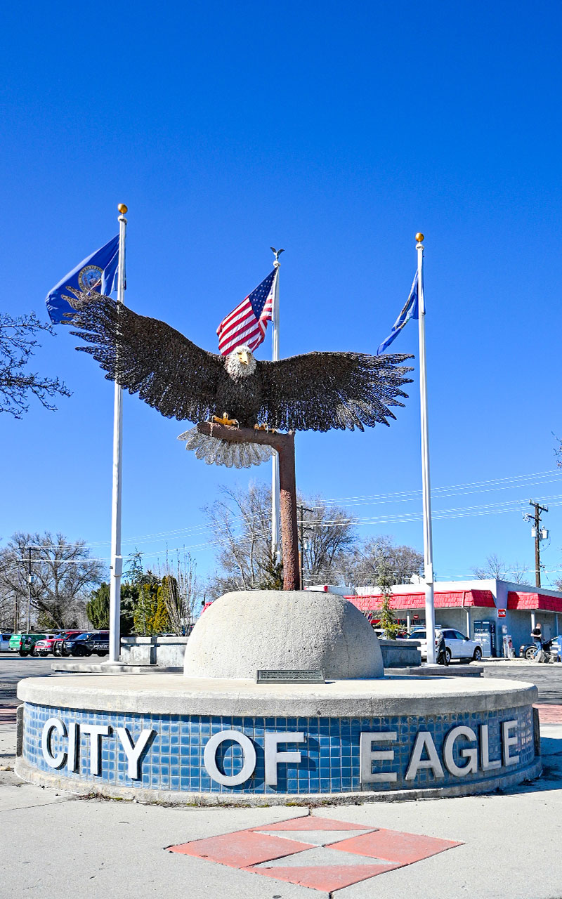 City of Eagle mural with a large wire eagle and 3 flags in the background.