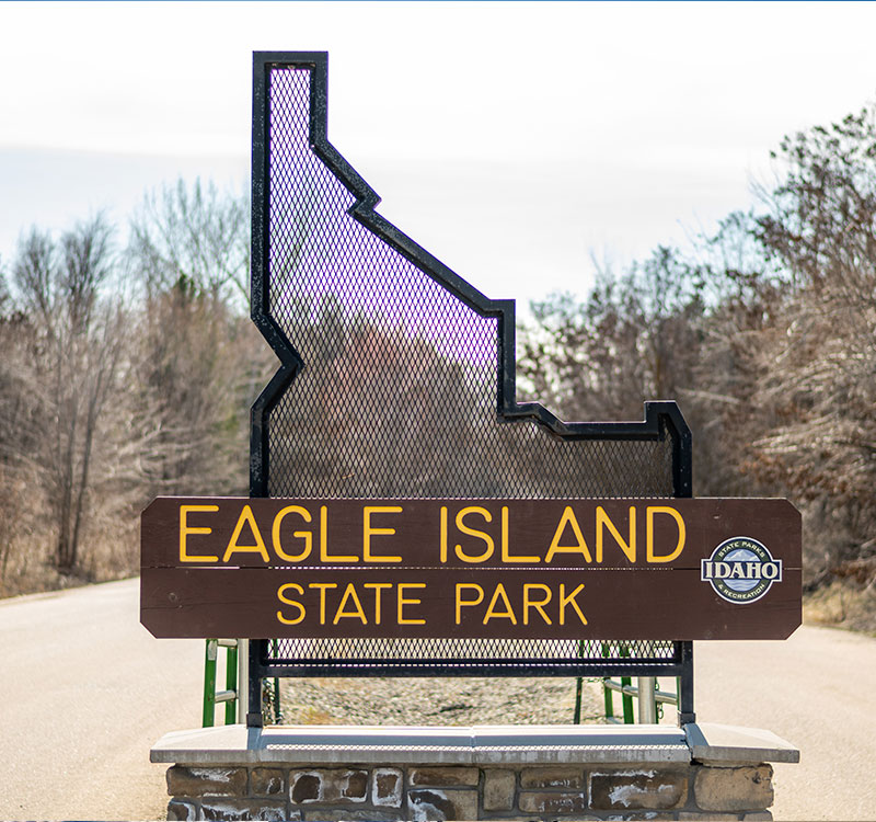 Sign for Eagle Island State Park. Wood sign set on a metal outline of the state of Idaho.