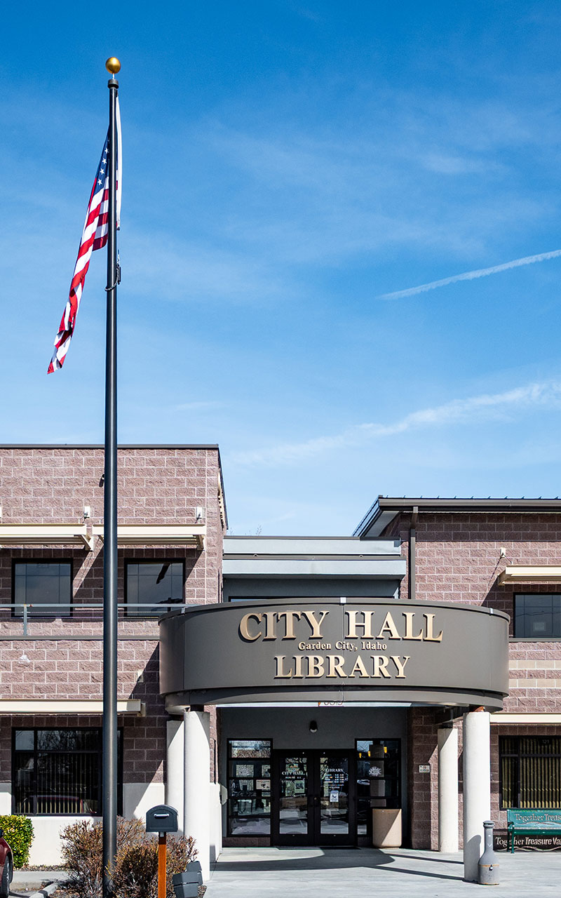 The City Hall and Library in Garden City on a bright day with an American flag out front.