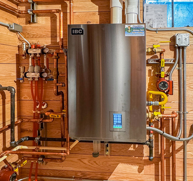 Boiler in a corner with pipes snaking along wall.