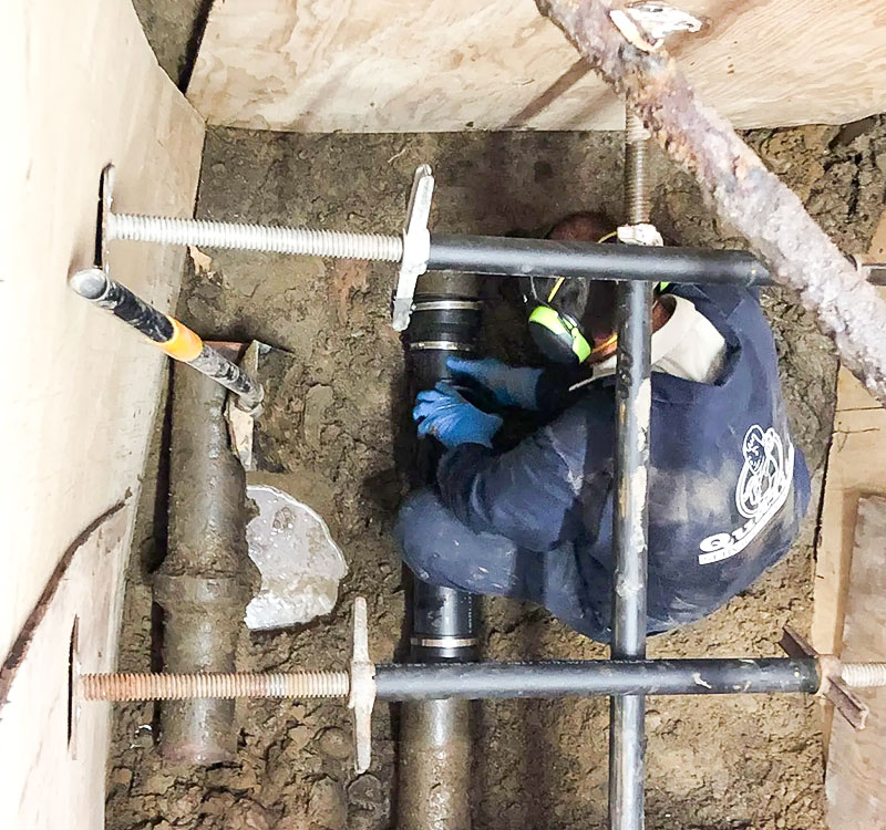 Plumber working in a small space on a sewer line repair.