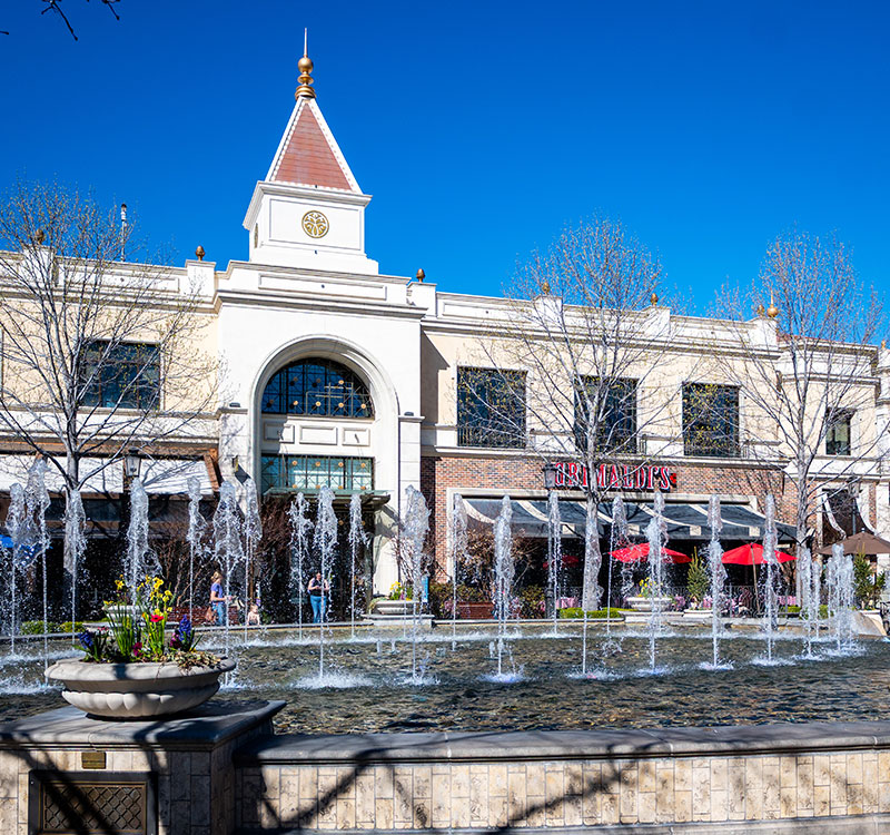 The Village in Meridian with a water fountain and building in the background on a bright sunny day.