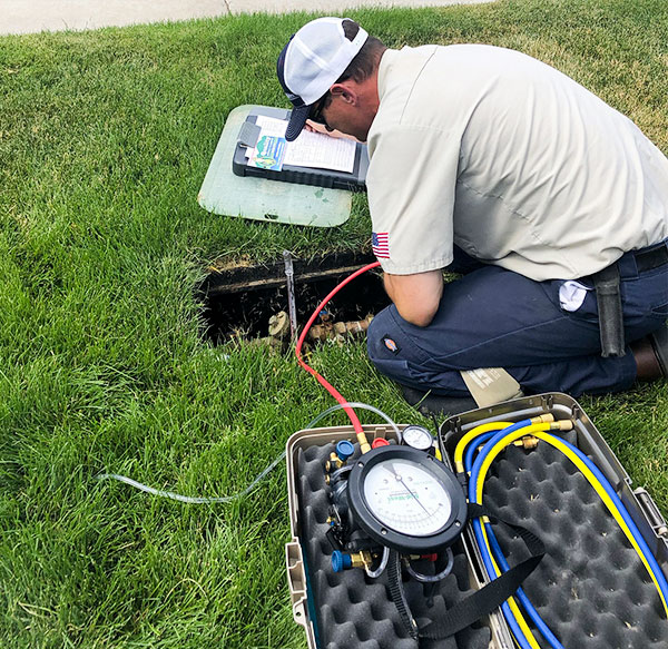 Plumbing technician inspecting a backflow line in the yard.