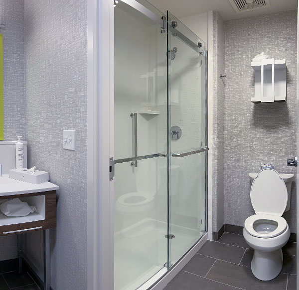 A commercial hotel bathroom showing a toilet and shower.