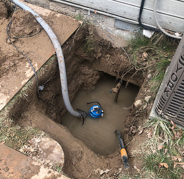 A waterline repair in the ground with water filling the hole.