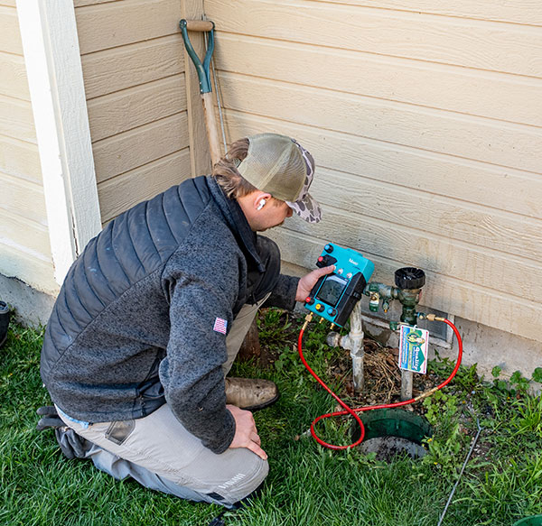 Plumbing technician checking the backflow of a sprinkler system.