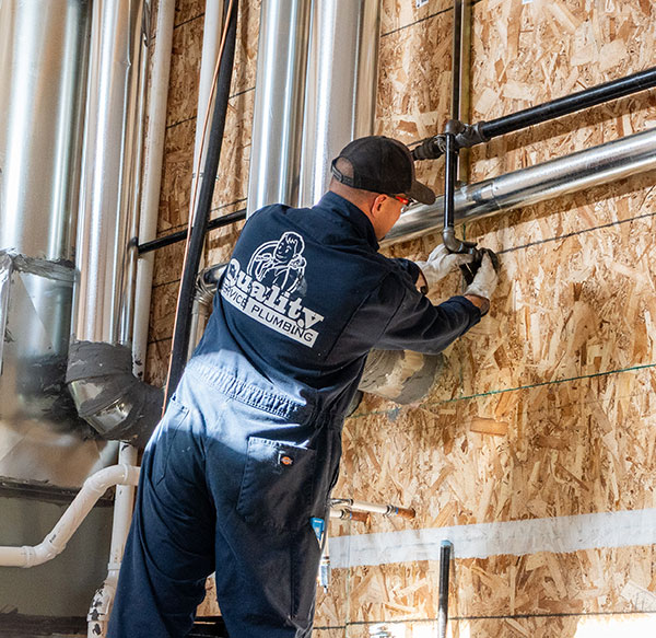 Plumbing technician on a ladder installing a new pipe gas line.
