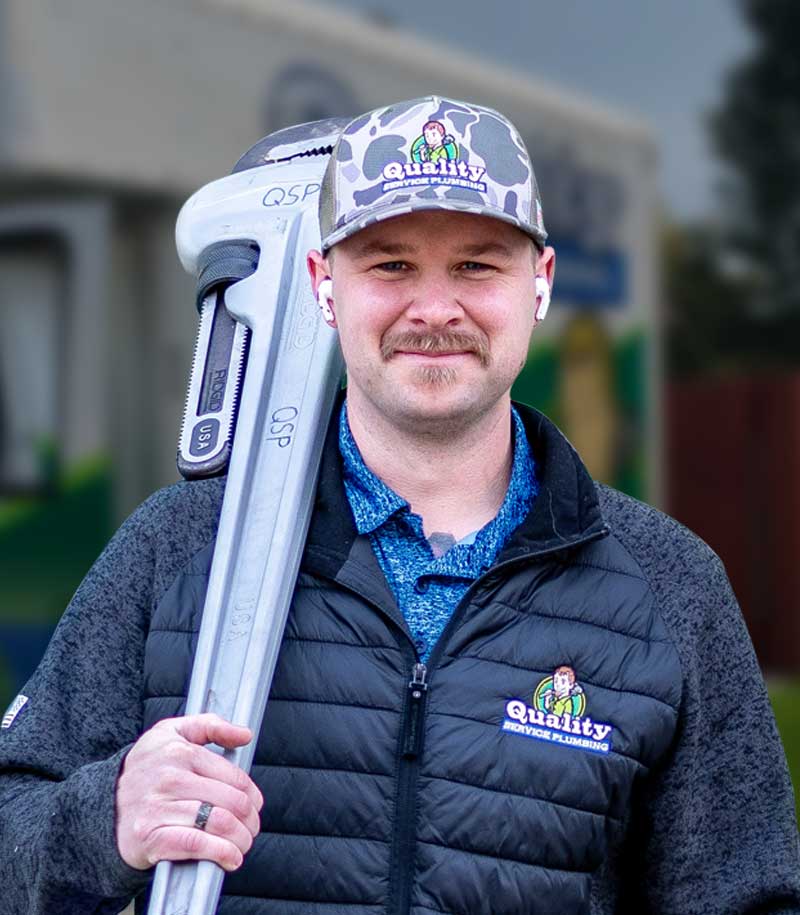 Local plumber smiling with a large pipe wrench.