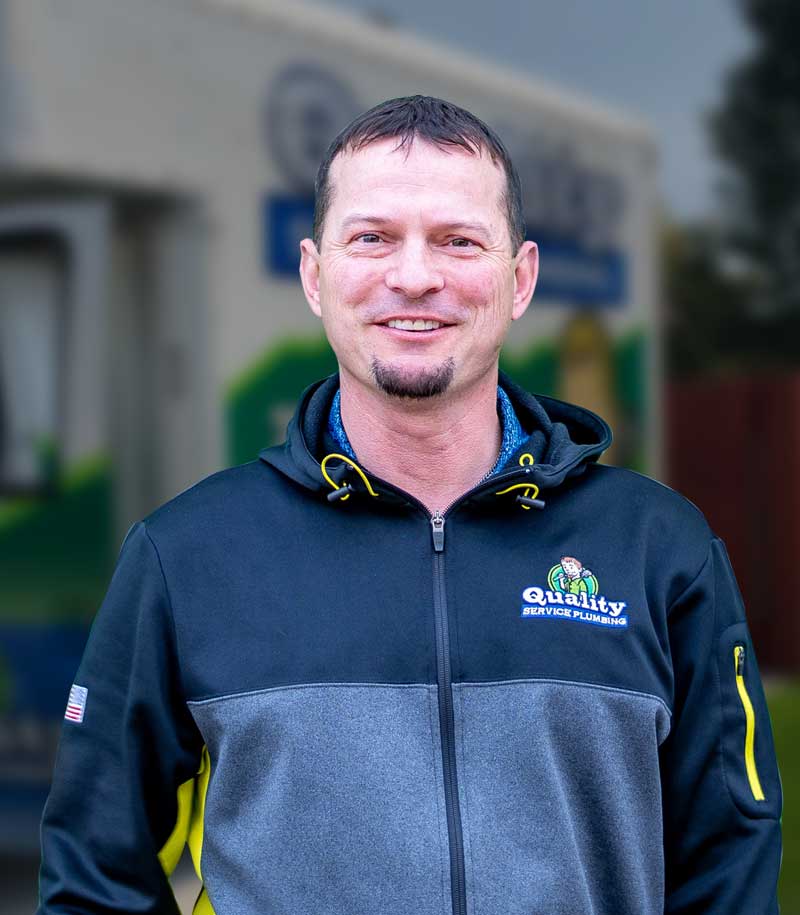 Local plumber smiling with company logo on jacket.