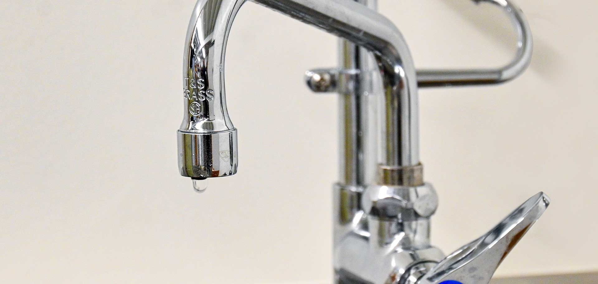 A drip of water coming out of a kitchen faucet.