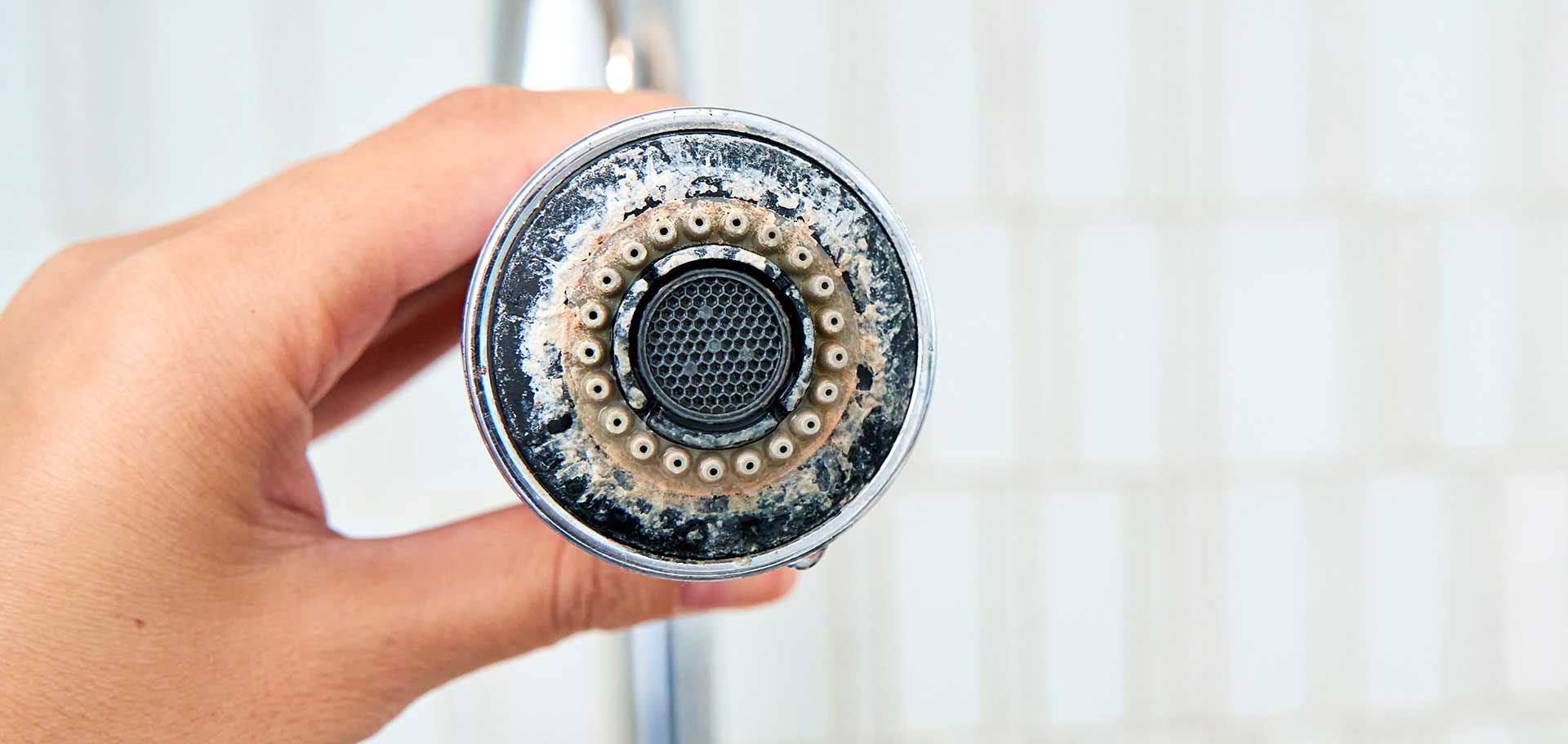 Hard water mineral build up on a kitchen sink faucet head.